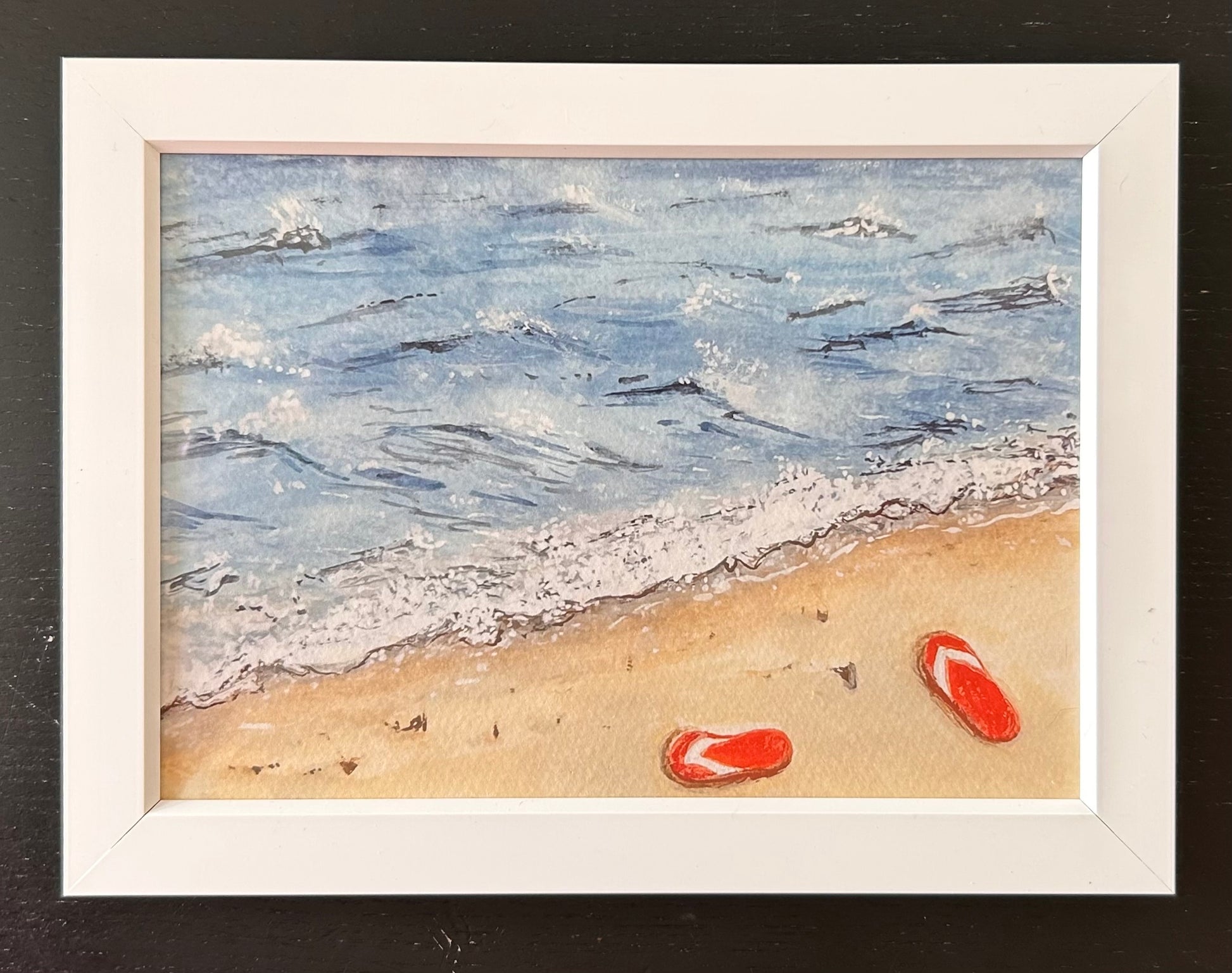 Framed artwork of a beach scene with waves and flip-flops.