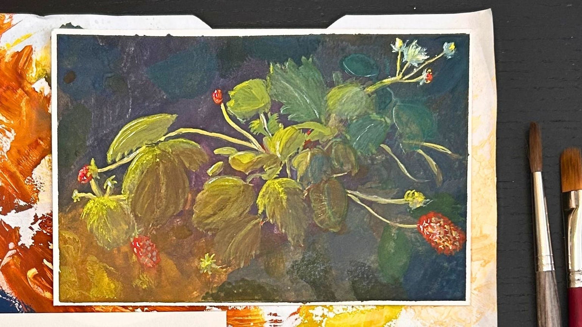 An original gouache painting of a strawberry plant with green leaves and red berries, displayed on a dark wooden surface with paint brushes and a paint palette visible around it.